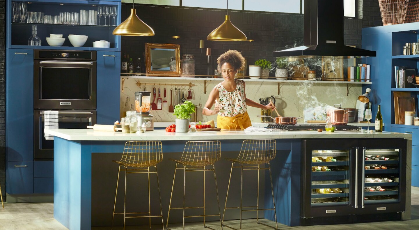 Woman preparing food in a blue kitchen with black stainless steel appliances Woman preparing food in a blue kitchen with black stainless steel appliances